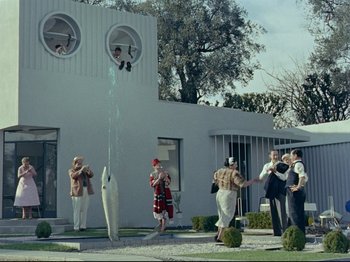 Movie still from “My Uncle” (1958), directed by Jacques Tati – A group of people standing in front of a fountain; Extreme Wide shot, Low angle