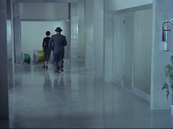 Movie still from “My Uncle” (1958), directed by Jacques Tati – A man and a woman walking down a hall way; Extreme Wide shot, High angle