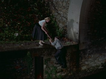 Movie still from “My Uncle” (1958), directed by Jacques Tati – A woman helping a man fall off of a bridge; Wide shot, Overhead angle