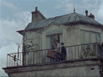 Movie still from “My Uncle” (1958), directed by Jacques Tati – Two people on a balcony with a suitcase; Wide shot, Low angle