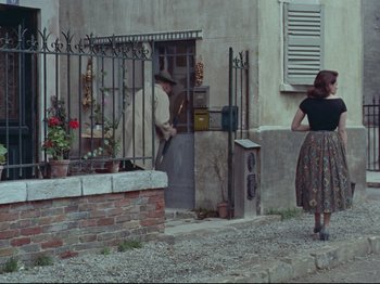 Movie still from “My Uncle” (1958), directed by Jacques Tati – A man and a woman standing in front of a building; Wide shot, Over the shoulder angle