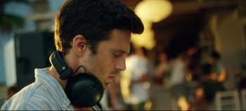 Movie still from “Monday” (2020), directed by Argyris Papadimitropoulos – A person wearing a pair of headphones; Close Up shot, Low angle