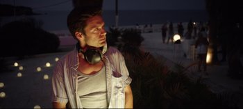 Movie still from “Monday” (2020), directed by Argyris Papadimitropoulos – A man with headphones standing next to a tree; Medium shot, Low angle