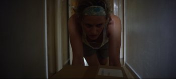 Movie still from “Monday” (2020), directed by Argyris Papadimitropoulos – A woman is bending over looking at a box; Close Up shot, Low angle