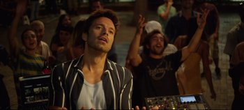 Movie still from “Monday” (2020), directed by Argyris Papadimitropoulos – A man is standing in front of a group of people; Medium shot, Low angle