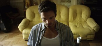 Movie still from “Monday” (2020), directed by Argyris Papadimitropoulos – A person sitting in a room; Medium shot, Low angle