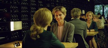 Movie still from “Monday” (2020), directed by Argyris Papadimitropoulos – A woman sitting at a table talking to another woman; Medium shot, Over the shoulder angle