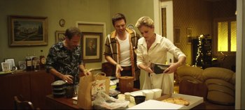 Movie still from “Monday” (2020), directed by Argyris Papadimitropoulos – A group of people standing around a table with food; Medium shot, High angle