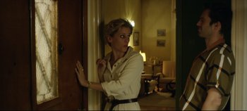 Movie still from “Monday” (2020), directed by Argyris Papadimitropoulos – A woman standing in front of a door in a living room; Medium shot, Over the shoulder angle