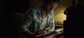 Movie still from “Monday” (2020), directed by Argyris Papadimitropoulos – A man is playing a keyboard in a recording studio; Medium shot, Low angle