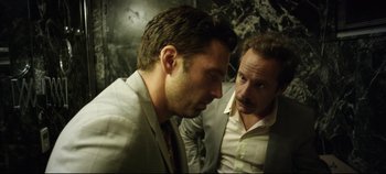 Movie still from “Monday” (2020), directed by Argyris Papadimitropoulos – Two men in suits are talking to each other; Close Up shot, Low angle