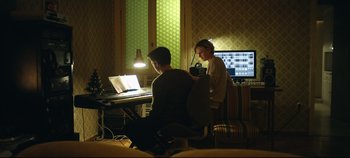 Movie still from “Monday” (2020), directed by Argyris Papadimitropoulos – A man and a woman sitting in front of a computer; Medium shot, Low angle