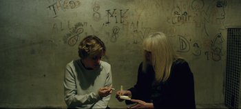 Movie still from “Monday” (2020), directed by Argyris Papadimitropoulos – Two people are looking at each other while one is holding a cigarette; Medium shot, Overhead angle