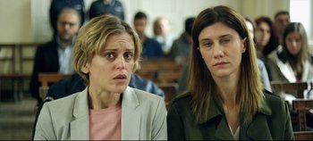 Movie still from “Monday” (2020), directed by Argyris Papadimitropoulos – Two women in a court room looking at the camera; Close Up shot, Over the shoulder angle