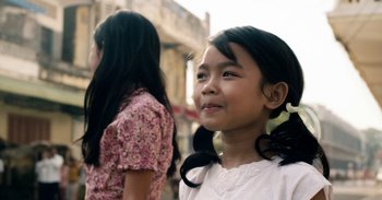 Movie still from “First They Killed My Father” (2017), directed by Angelina Jolie – Two young girls are standing together outside; Close Up shot, Over the shoulder angle