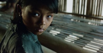 Movie still from “First They Killed My Father” (2017), directed by Angelina Jolie – A young person with blue eyes; Close Up shot, Over the shoulder angle