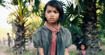 Movie still from “First They Killed My Father” (2017), directed by Angelina Jolie – A little girl wearing a red and white neck scarf; Close Up shot, Over the shoulder angle