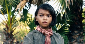 Movie still from “First They Killed My Father” (2017), directed by Angelina Jolie – A little girl with black hair wearing a jacket and a scarf; Close Up shot, Low angle