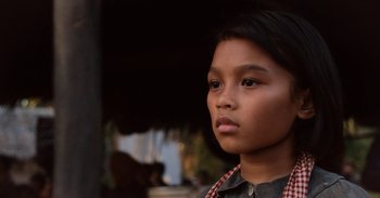Movie still from “First They Killed My Father” (2017), directed by Angelina Jolie – A young girl is standing in front of an umbrella; Close Up shot, Low angle