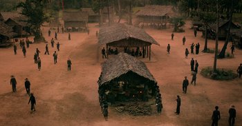 Movie still from “First They Killed My Father” (2017), directed by Angelina Jolie – A group of people standing around a hut; Extreme Wide shot, High angle