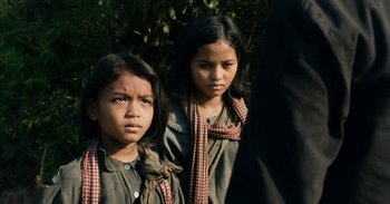 Movie still from “First They Killed My Father” (2017), directed by Angelina Jolie – Two young girls are posing for a picture; Close Up shot, Low angle
