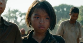 Movie still from “First They Killed My Father” (2017), directed by Angelina Jolie – A young girl's face with trees in the background; Close Up shot, Low angle