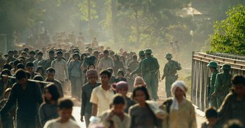 Movie still from “First They Killed My Father” (2017), directed by Angelina Jolie – A large group of people walking down a dirt road; Extreme Wide shot, High angle