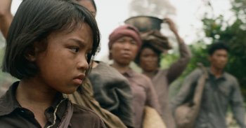 Movie still from “First They Killed My Father” (2017), directed by Angelina Jolie – A group of people standing next to each other on a field; Close Up shot, Over the shoulder angle