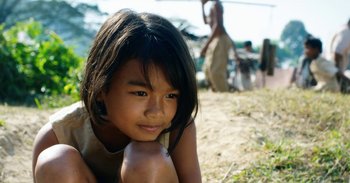 Movie still from “First They Killed My Father” (2017), directed by Angelina Jolie – A little girl sitting on the ground in the dirt; Close Up shot, Low angle