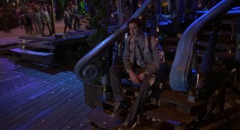 Movie still from “Monkeybone” (2001), directed by Henry Selick – A man sitting on top of a chair next to stairs; Wide shot, High angle