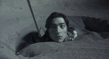 Movie still from “Monkeybone” (2001), directed by Henry Selick – A man with a knife in his hand in the sand; Close Up shot, High angle