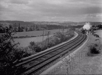 Movie still from “Monsieur Hulot's Holiday” (1953), directed by Jacques Tati – A train traveling down the tracks near a field; Extreme Wide shot, High angle