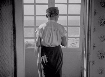 Movie still from “Monsieur Hulot's Holiday” (1953), directed by Jacques Tati – An older woman standing in front of a window; Wide shot, Low angle