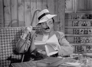 Movie still from “Monsieur Hulot's Holiday” (1953), directed by Jacques Tati – A black and white photo of a man sitting at a table; Medium shot, High angle