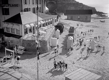 Movie still from “Monsieur Hulot's Holiday” (1953), directed by Jacques Tati – A black - and - white photo of people on the beach; Extreme Wide shot, High angle