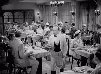 Movie still from “Monsieur Hulot's Holiday” (1953), directed by Jacques Tati – A group of people sitting at tables in a restaurant; Wide shot, High angle