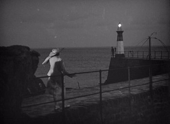 Movie still from “Monsieur Hulot's Holiday” (1953), directed by Jacques Tati – A woman walking on a pier near the ocean; Extreme Wide shot, High angle