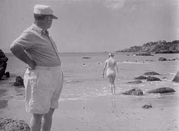 Movie still from “Monsieur Hulot's Holiday” (1953), directed by Jacques Tati – An old photo of a man and a woman on the beach; Medium shot, Over the shoulder angle