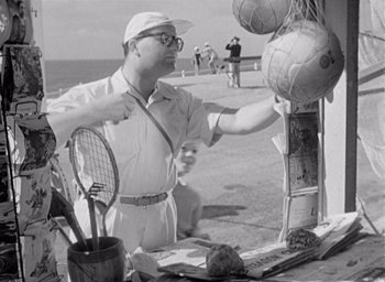 Movie still from “Monsieur Hulot's Holiday” (1953), directed by Jacques Tati – An old photo of a man holding a tennis racquet; Medium shot, Low angle