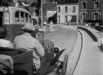 Movie still from “Monsieur Hulot's Holiday” (1953), directed by Jacques Tati – An old photo of a man driving a car down a street; Wide shot, High angle