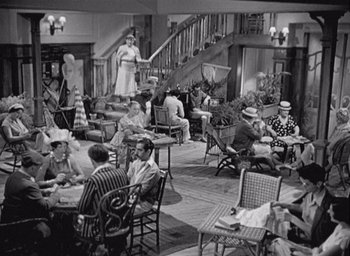 Movie still from “Monsieur Hulot's Holiday” (1953), directed by Jacques Tati – A group of people sitting at tables in a living room; Wide shot, High angle