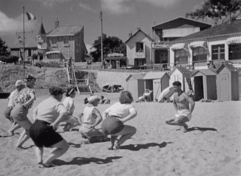 Movie still from “Monsieur Hulot's Holiday” (1953), directed by Jacques Tati – A black and white photo of people on the beach; Wide shot, High angle
