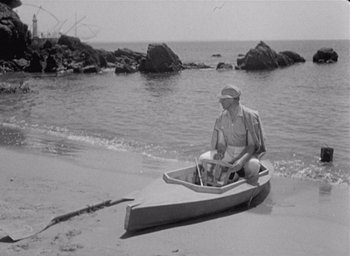 Movie still from “Monsieur Hulot's Holiday” (1953), directed by Jacques Tati – An older man sitting in a boat on the beach; Wide shot, High angle