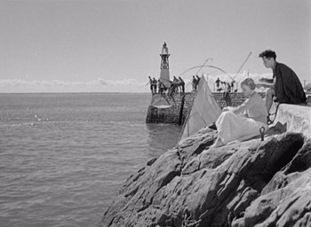 Movie still from “Monsieur Hulot's Holiday” (1953), directed by Jacques Tati – A black and white photo of people standing on a pier; Extreme Wide shot, High angle