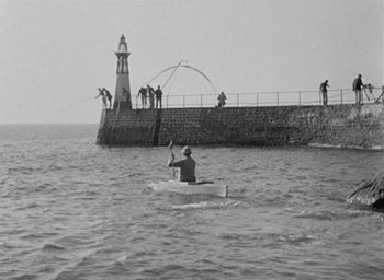 Movie still from “Monsieur Hulot's Holiday” (1953), directed by Jacques Tati – A man is in a boat in the water; Extreme Wide shot, High angle