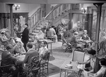 Movie still from “Monsieur Hulot's Holiday” (1953), directed by Jacques Tati – A group of people sitting at tables in a room; Wide shot, High angle