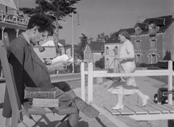 Movie still from “Monsieur Hulot's Holiday” (1953), directed by Jacques Tati – A man sitting on a chair in front of a woman; Wide shot, Low angle