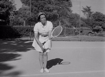 Movie still from “Monsieur Hulot's Holiday” (1953), directed by Jacques Tati – An older woman holding a tennis racket on a court; Medium shot, Low angle