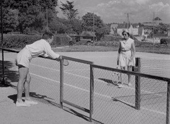 Movie still from “Monsieur Hulot's Holiday” (1953), directed by Jacques Tati – A man and a woman playing tennis on a tennis court; Wide shot, Low angle