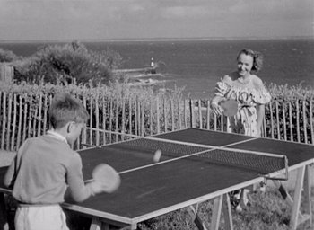 Movie still from “Monsieur Hulot's Holiday” (1953), directed by Jacques Tati – Two children playing a game of ping pong on the beach; Wide shot, High angle